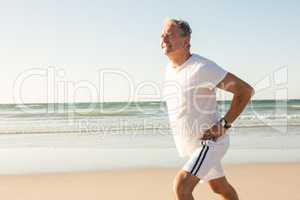 Senior man running on shore against clear sky