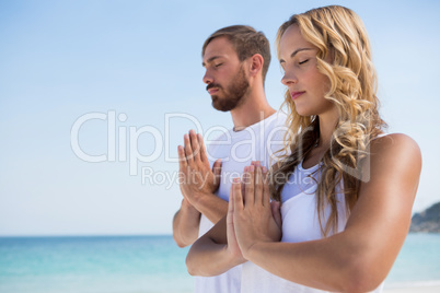 Couple with eyes closed exercising at beach