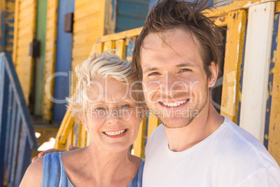 Smiling man with mother standing against beach hut