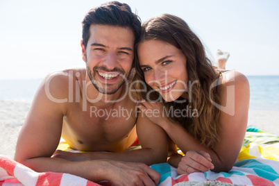 Portrait of smiling couple lying together on blanket at beach