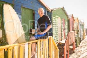 Senior man looking away while sitting on railing of hut