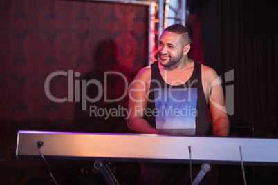 Happy musician playing piano at nightclub