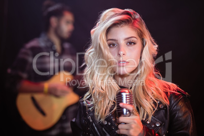 Portrait of female singer holding mic at nightclub