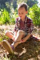 Boy tying shoelace in the forest