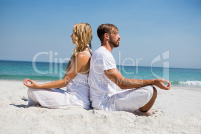 Side view of couple meditating at beach