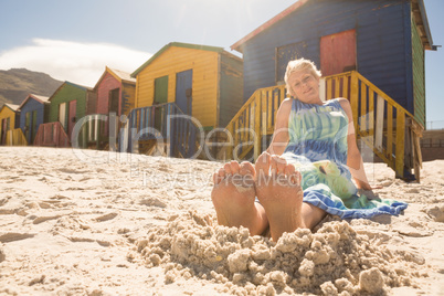 Woman relaxing on sand against huts at beach