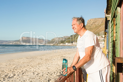 Side view of senior man standing on railing at beach