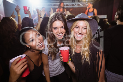 Portrait of female friends with disposable cups in club