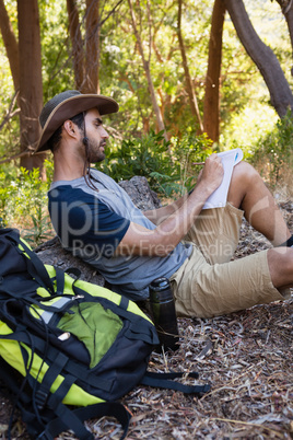 Man writing on notepad while resting on tree trunk