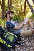 Man writing on notepad while resting on tree trunk