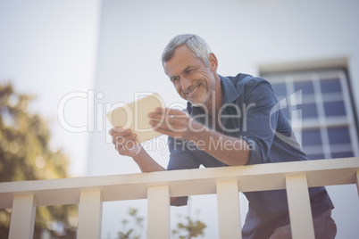 Mature man using digital tablet in balcony