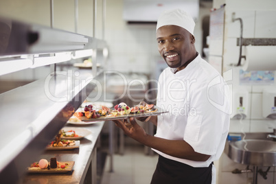 Chef holding dessert tray in commercial kitchen