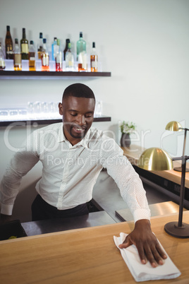 Bar tender cleaning bar counter in restaurant