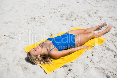 High angle view of woman sunbathing on sand at beach