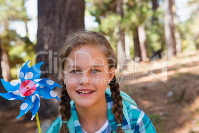 Smiling girl holding a pinwheel in the forest