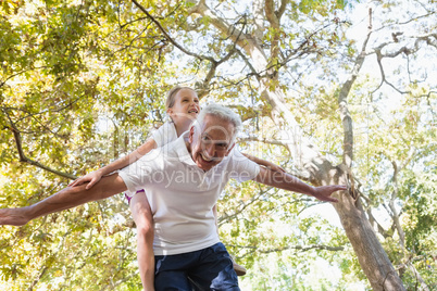 Grandfather giving granddaughter piggy back in the forest