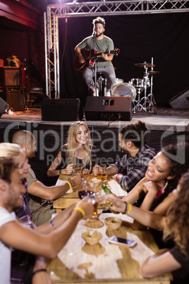 Male musician singing with fans sitting at table