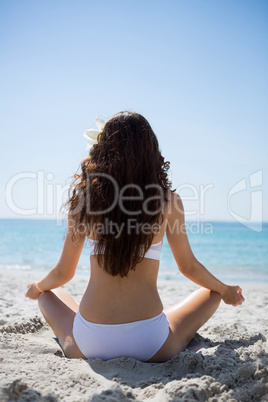 Rear view of woman exercising at beach