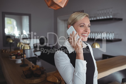 Smiling waitress talking on mobile phone