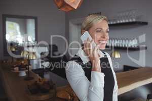 Smiling waitress talking on mobile phone