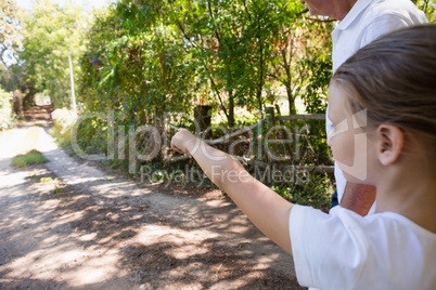 Girl with her grandfather pointing at a distance in the forest