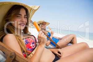 Portrait of female friends holding popsicles while sitting on deck chair