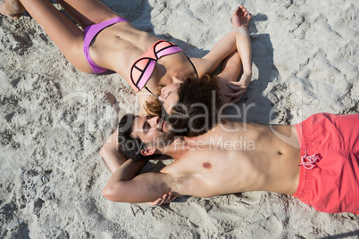 Overhead view of young couple lying together on sand at beach
