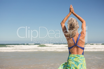 Woman practising yoga while standing at beach