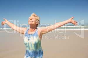 Happy woman with arms outstretched standing against clear sky
