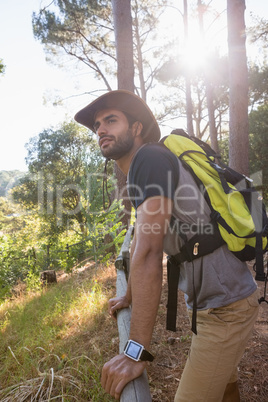 Man with backpack leaning on wooden fence in the forest