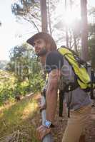 Man with backpack leaning on wooden fence in the forest