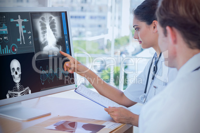 Composite image of doctor pointing at the screen of a computer