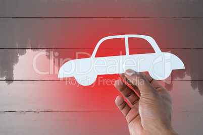 Composite image of hand holding a car in paper