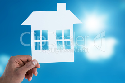 Composite image of hand holding a house in paper