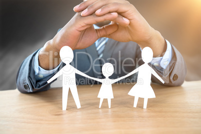 Composite image of hand protecting a family in paper