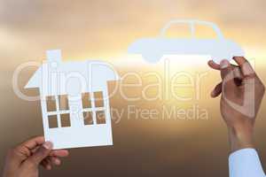 Composite image of man holding a car and a house in paper