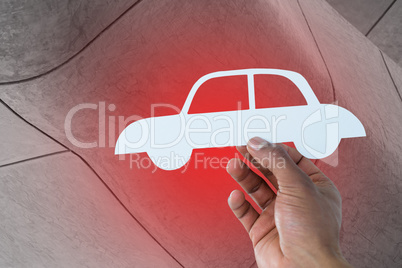 Composite image of hand holding a car in paper
