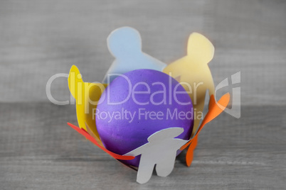 Multi colored paper cut out figures forming circle around ball