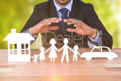 Composite image of underwriter protecting family in paper with his hands