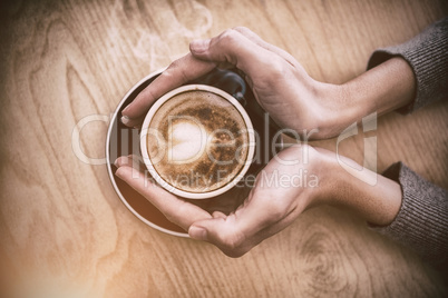 Woman holding cup of coffee on table