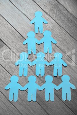 Paper cut out figures forming human pyramid on table