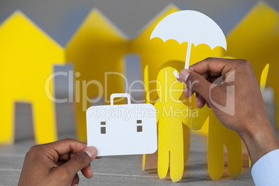 Composite image of hands holding a schoolbag and an umbrella in paper