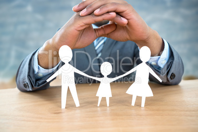 Composite image of hand protecting a family in paper