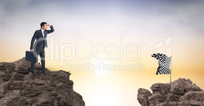 Businessman looking at flag on rock against sky
