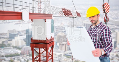 Male architect holding blue print by crane at construction site