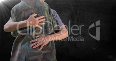 Soldier hugging mid section against black background and flare