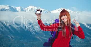 Happy female hiker taking selfie through smart phone against snow covered mountain