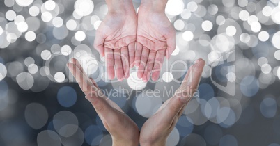 Cropped image of hands against glowing bokeh