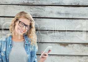 Portrait of smiling woman holding smart phone against wooden wall