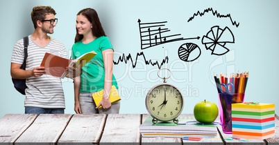 Male and female students with books at desk against graphics